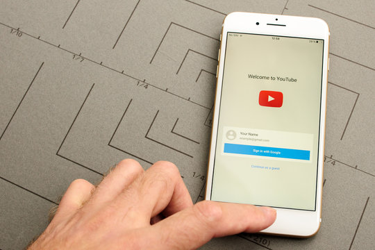 PARIS, FRANCE - SEPT 26, 2016: New iPhone 7 Plus with hand touching screen to sign-in to Youtube video sharing social network. iPhone 7 and iPhone 7 plus is the most wanted phone worldwide