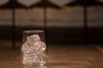 A sturdy glass cup with ice cubes on a wooden table