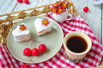 Valentine`s Day breakfast two heart honey cakes on ceramic plate with red fabric and red apples and red flowers on white wooden table,top view,romantic morning food