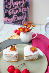 Valentine`s Day breakfast two heart honey cakes on ceramic plate with red fabric and red apples and red flowers on white wooden table,top view,romantic morning food