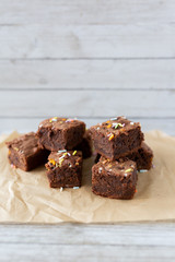 Banana brownies with multi colored sprinkles, crinkled parchment paper, wooden background