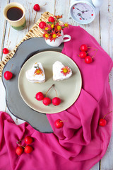 Valentine`s Day breakfast two heart honey cakes on ceramic plate with red fabric and red apples and red flowers on white wooden table,top view,romantic morning food