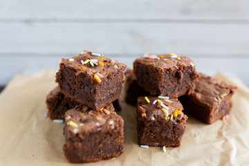 Banana brownies with multi colored sprinkles, crinkled parchment paper, wooden background
