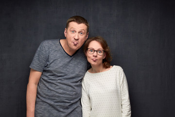 Portrait of funny couple grimacing and showing tongues