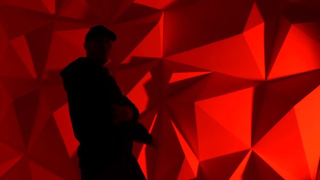 Rapper man dancing to the music. Silhouette on a dark red background