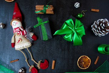 Christmas background with dry orange,white pinecone,green christmas tree balls,mandarins,red apple,ginger sticks,on a black background,flat lay,space for text,space for copy