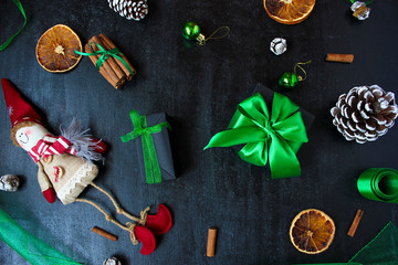 Christmas background with dry orange,white pinecone,green christmas tree balls,mandarins,red apple,ginger sticks,on a black background,flat lay,space for text,space for copy