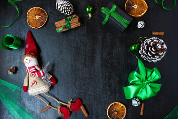 Christmas background with dry orange,white pinecone,green christmas tree balls,mandarins,red apple,ginger sticks,on a black background,flat lay,space for text,space for copy