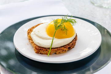 Mango meringue sculptured in the shape of a fried egg, on a slice of toast.