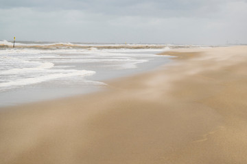 Fototapeta na wymiar Tidal waves at beach near the Hague, the Netherlands, in windy day. North sea abstract natural background in June.