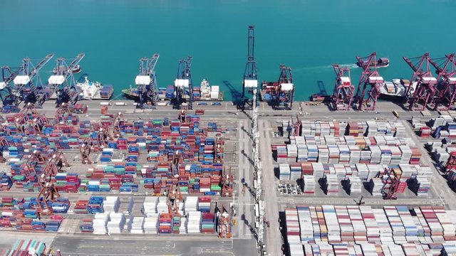 Aerial panorama of well organized storage at large container terminal. Many intermodal containers stacked around dockyard in perfect order, gantry cranes at pier, several containerships moored at port