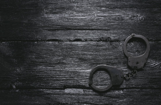 Handcuffs on wooden black table flat lay background with copy space.