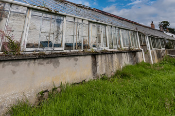 Old, abandoned greenhouse with broken glass panes and windows.