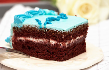 Piece of homemade chocolate cake with blue buttercream white plate. Selective focus. Close up.