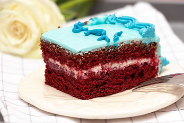 Pieces homemade Red Velvet cake with blue buttercream white plate. Selective focus. Close up.