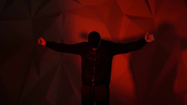 Rapper man dancing to the music. Silhouette on a dark red background