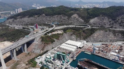 Industrial facility and docks at reclaimed land, large interchange in front of Tsing Ma bridge. Cut hill sides of Tsing Yi island for development, aerial shot