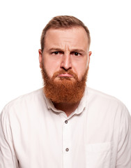 Obraz premium Portrait of a young, chubby, redheaded man in a white shirt making faces at the camera, isolated on a white background
