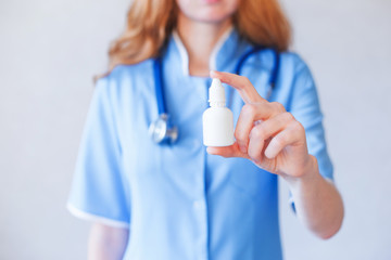 Doctor holding a spray or nasal drops for the treatment of a runny nose.