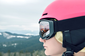Close up portrait of snowboarder woman at ski resort wearing helmet and goggles with reflection of...