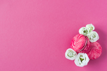 Composition of two pink French macarons and white flowers. Flat lay, place for text.