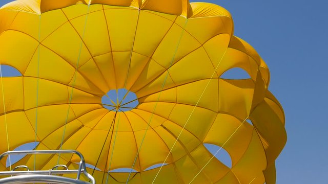 Yellow bright parasailing parachute flying against blue sky with copy space. Outdoor extreme sport summer activity for tourists