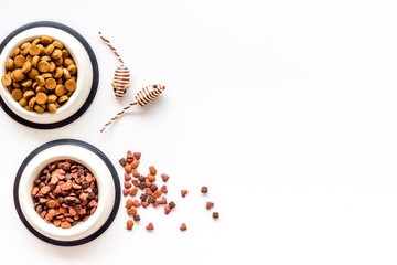 Cat dry food in bowl and toys, grooming tools on white background top view copyspace