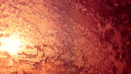 Ice patterns on winter glass of window, with the light seen through it. Light coral duotone. Horizontal banner. Selective focus. Creative background about winter, cold, christmas time.