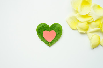 St. Valentine's day. The heart is cut out of paper and foliage on white background. Rose petals.