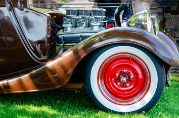 Side view of the engine and front red wheels of a hot rod