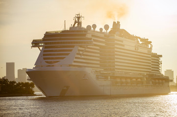 Golden backlit view of putrid brown exhaust smoke billowing from the smokestack of a cruise ship at...
