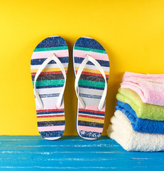 pair of female beach slippers and a  towels  on a blue yellow background