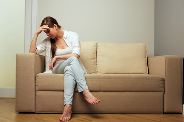 Tired woman in depression sitting on sofa