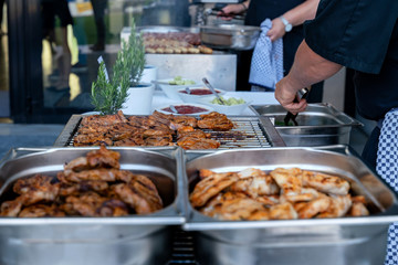 Meat sizzles on a large electric grill during a big barbecue party