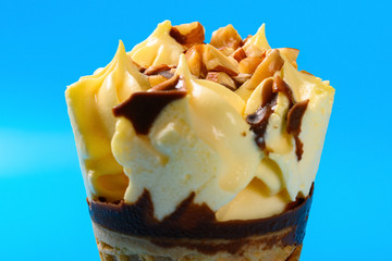 close up of mango and chocolate flavor ice cream cone with peanut on blue background