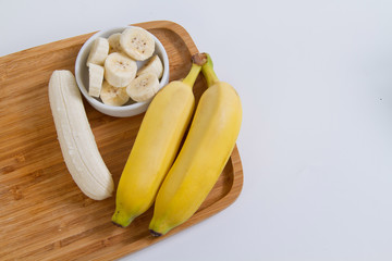 Banana em  prato de madeira no fundo branco