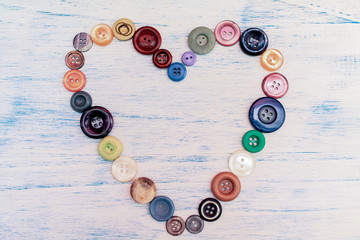 Heart of colorful buttons on rustic background.