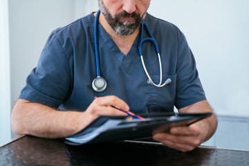 Professional cardiologist holding a folder with stethoscope. Close up and detail.