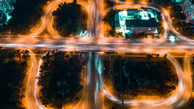 Aerial view of road junction cloverleaf crossing with car traffic in the big city at night. Time lapse. Hyperlapse