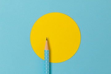 Top view of turquoise polka dot pencil on colorful paper combine with yellow circle