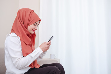 Muslim girl use smart mobile phone, hijab girl typing message at home