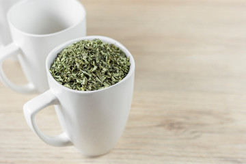 white cup with moringa leaves on wooden background