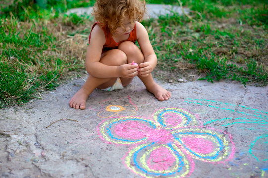 little girl draws a flower on the pavement, creativity of children