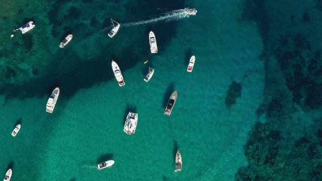View from above, stunning aerial view of the beautiful Cala Di Volpe bay full of boats and luxury yachts. A turquoise sea bathes the green and rocky coasts. Emerald Coast, Sardinia, Italy.
