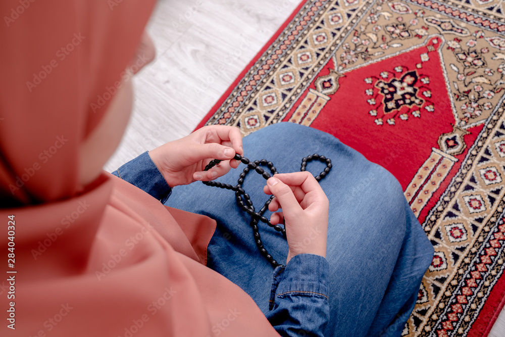 Wall mural muslim woman prayer, muslim girl open hands praying with rug