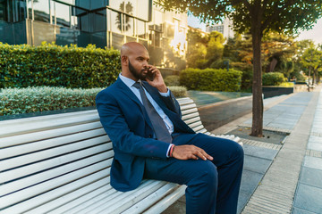 Indian businessman holding mobile phone wearing blue suit and using modern smartphone near office. Business concept