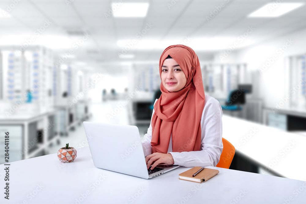 Wall mural Hijab muslim woman work with computer, muslim girl sitting in office and look at the camera