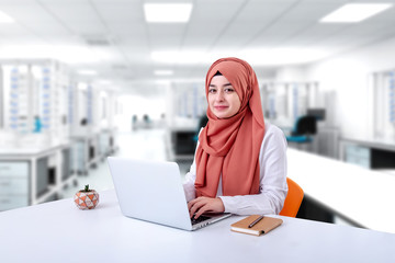 Hijab muslim woman work with computer, muslim girl sitting in office and look at the camera