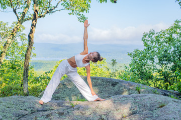 Young woman practicing yoga on stone outdoors harmony with nature.