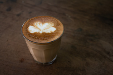Piccolo Latte art in paper cup on wooden desk